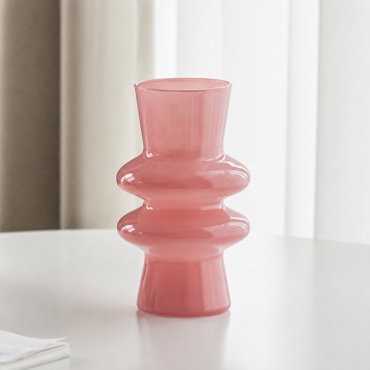 Pink modern sculptural glass flower vase on a white table