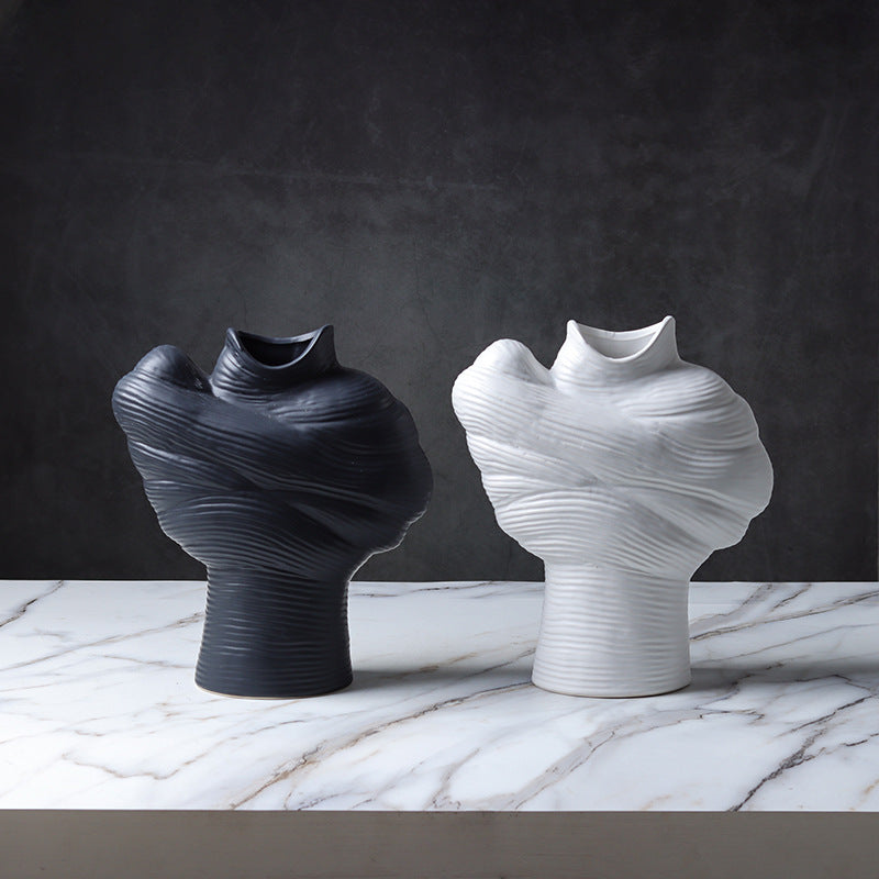 Black and white modern sculptural ribbed ceramic vases displayed on a marble table