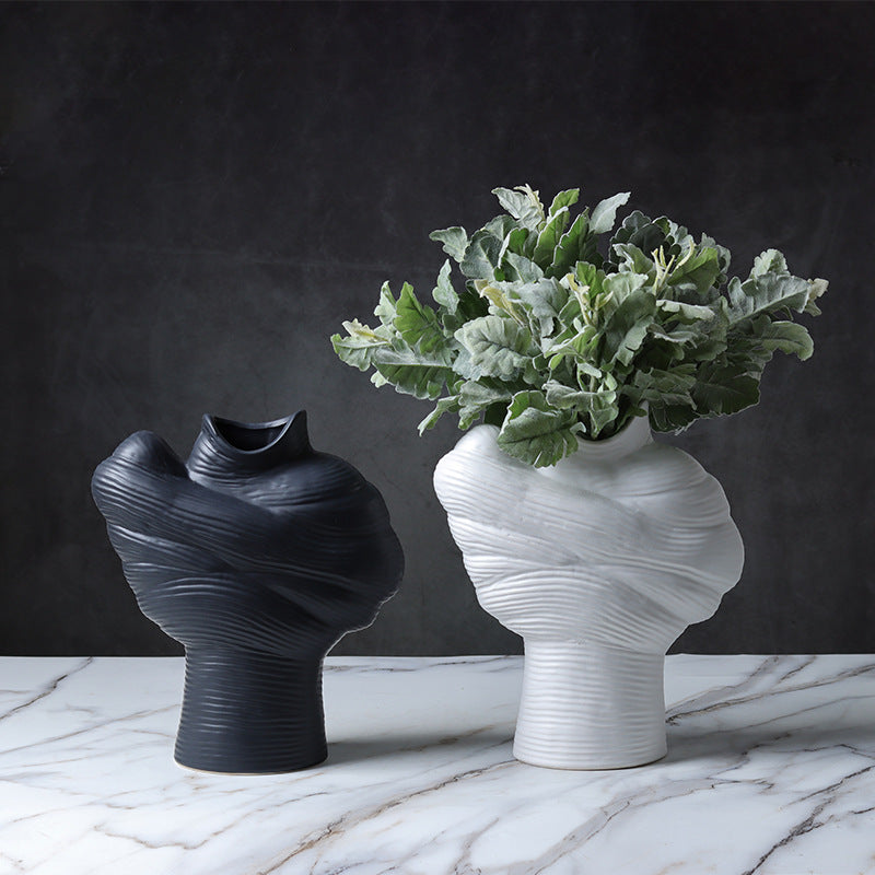 Black and white ribbed ceramic vases styled with green foliage