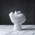 White abstract ribbed ceramic vase displayed on a marble surface