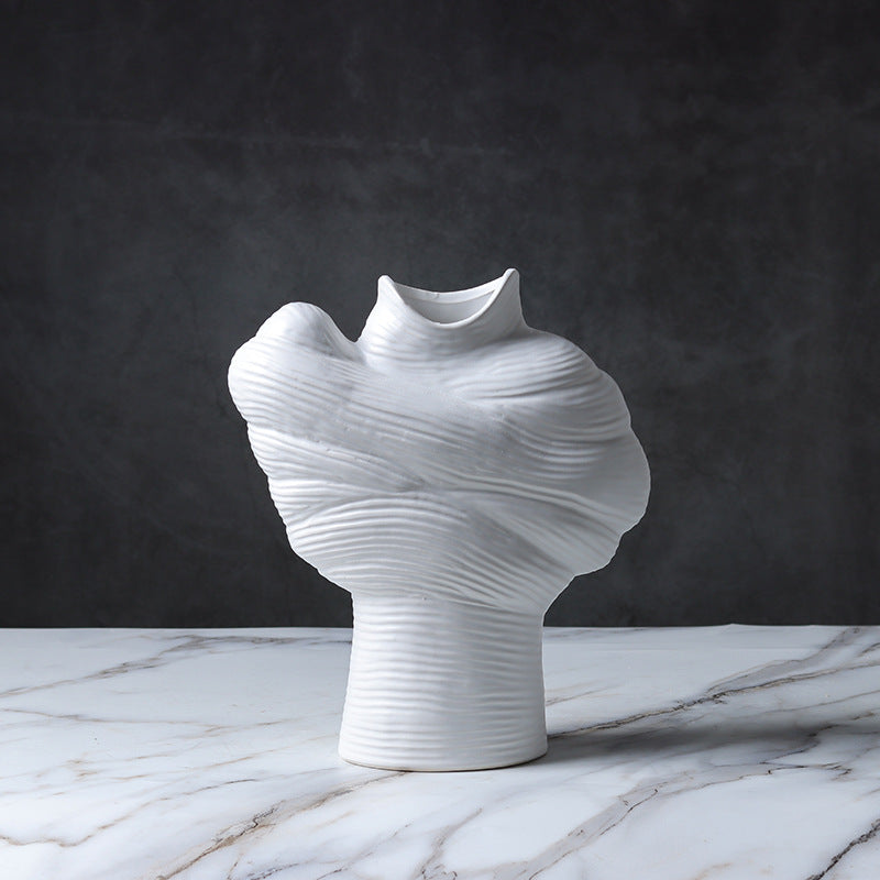White abstract ribbed ceramic vase displayed on a marble surface