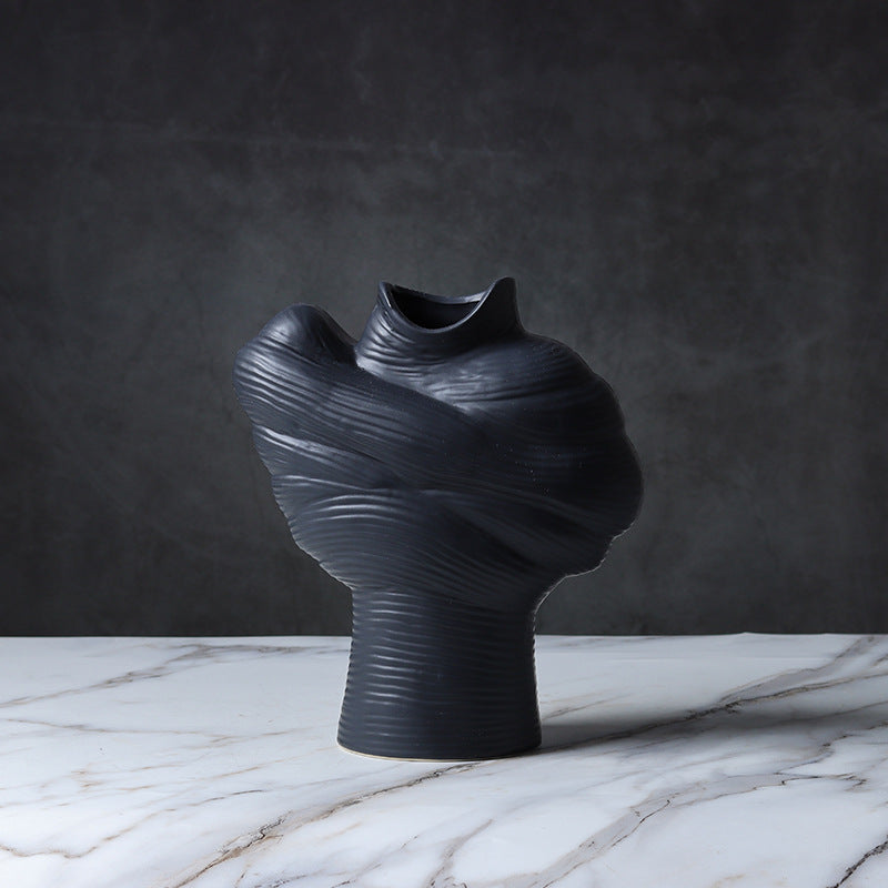 Black abstract ribbed ceramic vase displayed on a marble surface