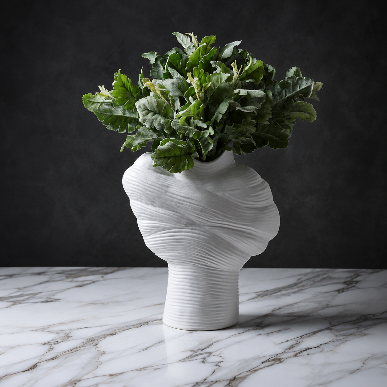 White modern sculptural ribbed ceramic vase styled with green foliage