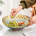 Hand arranging fruit in iridescent textured bubble glass centerpiece bowl