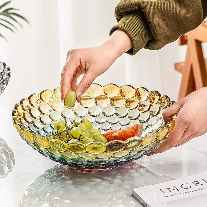 Hand arranging fruit in iridescent textured bubble glass centerpiece bowl