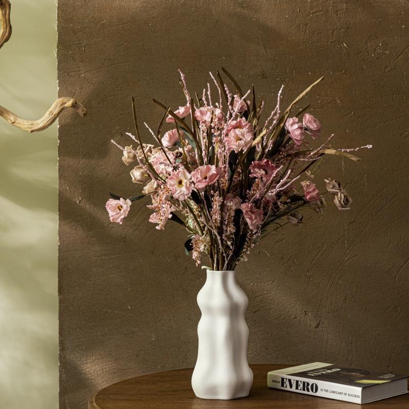White wavy ceramic flower vase styled with pink dried flowers on stacked books