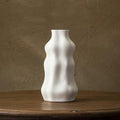 White modern wavy ceramic decorative vase on a wooden table