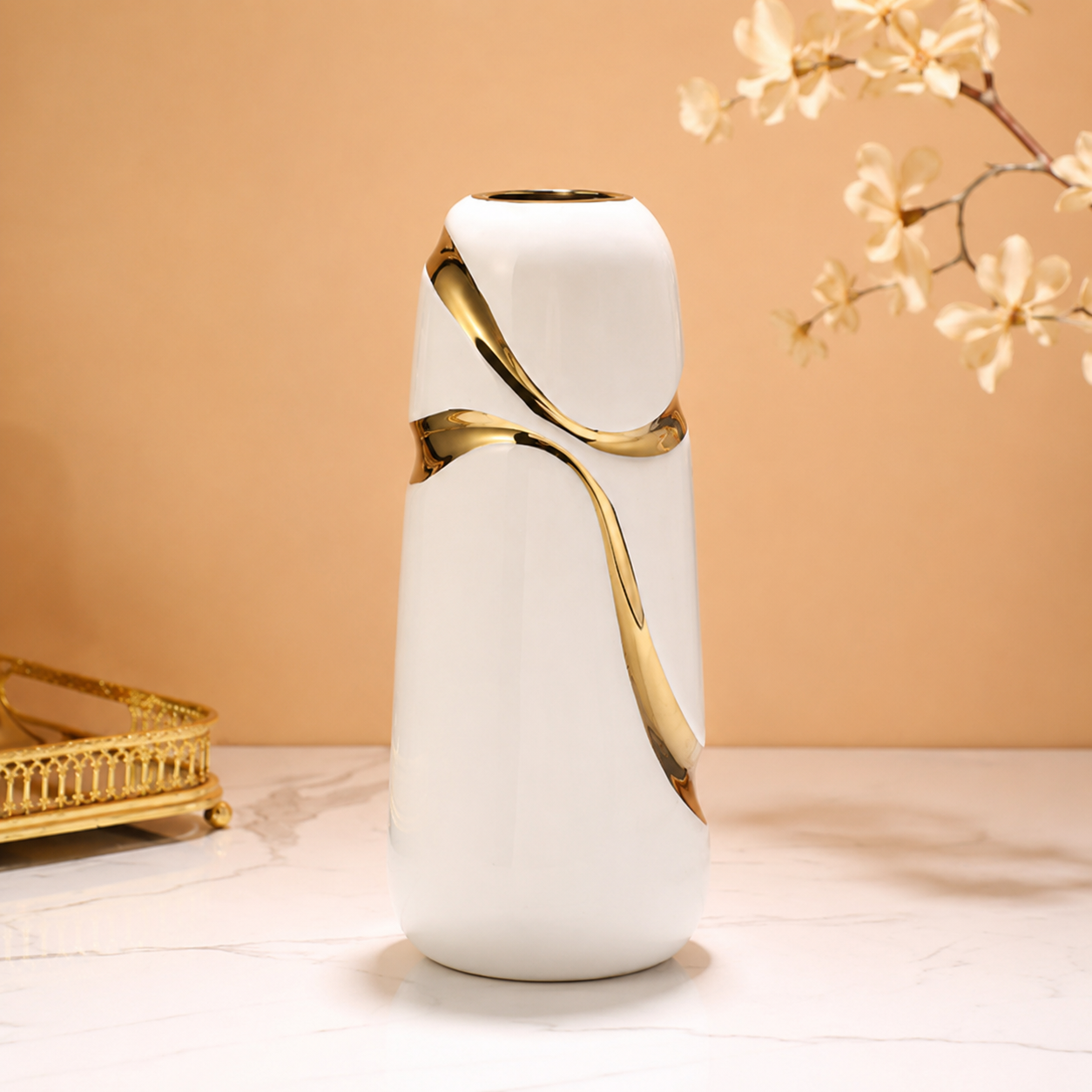 Tall modern white ceramic vase with gold ribbon accents on a marble tabletop