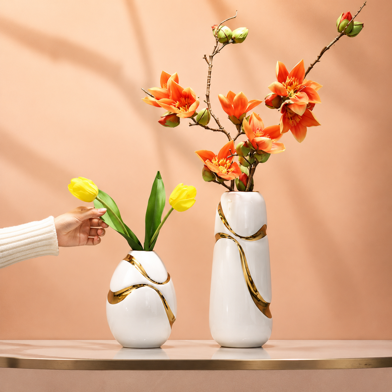 Modern white ceramic vases with gold accents styled with yellow and orange flowers