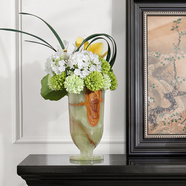 Green marble pedestal flower vase with white floral arrangement beside framed wall art