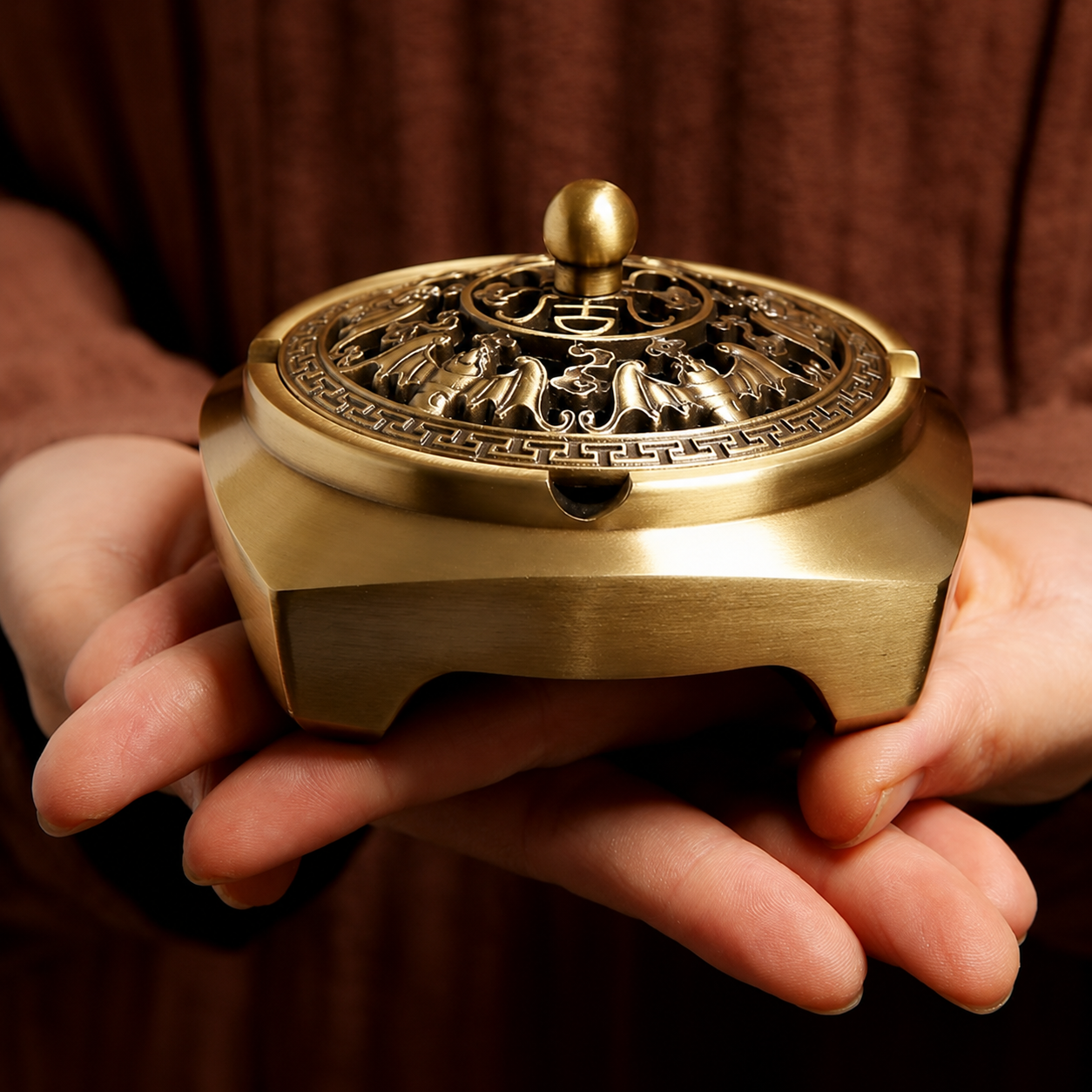 Person holding a decorative gold incense burner with intricate designs.