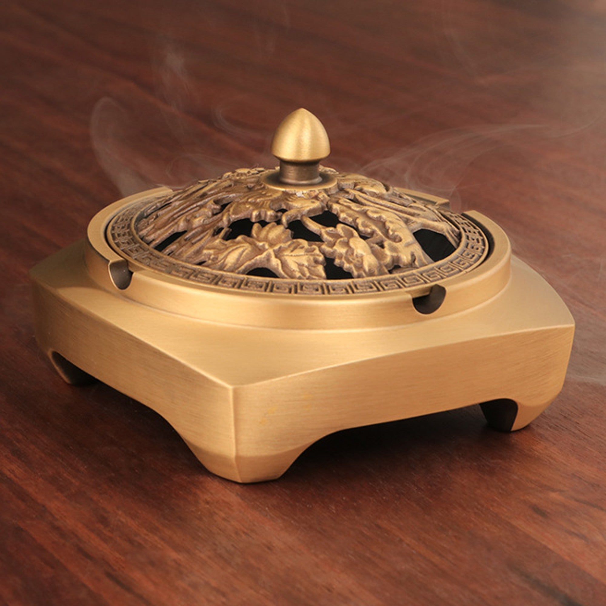 Gold brass incense burner with carved lid on wooden table