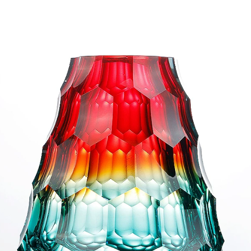Close up of red and teal faceted glass vase showing geometric texture and color gradient