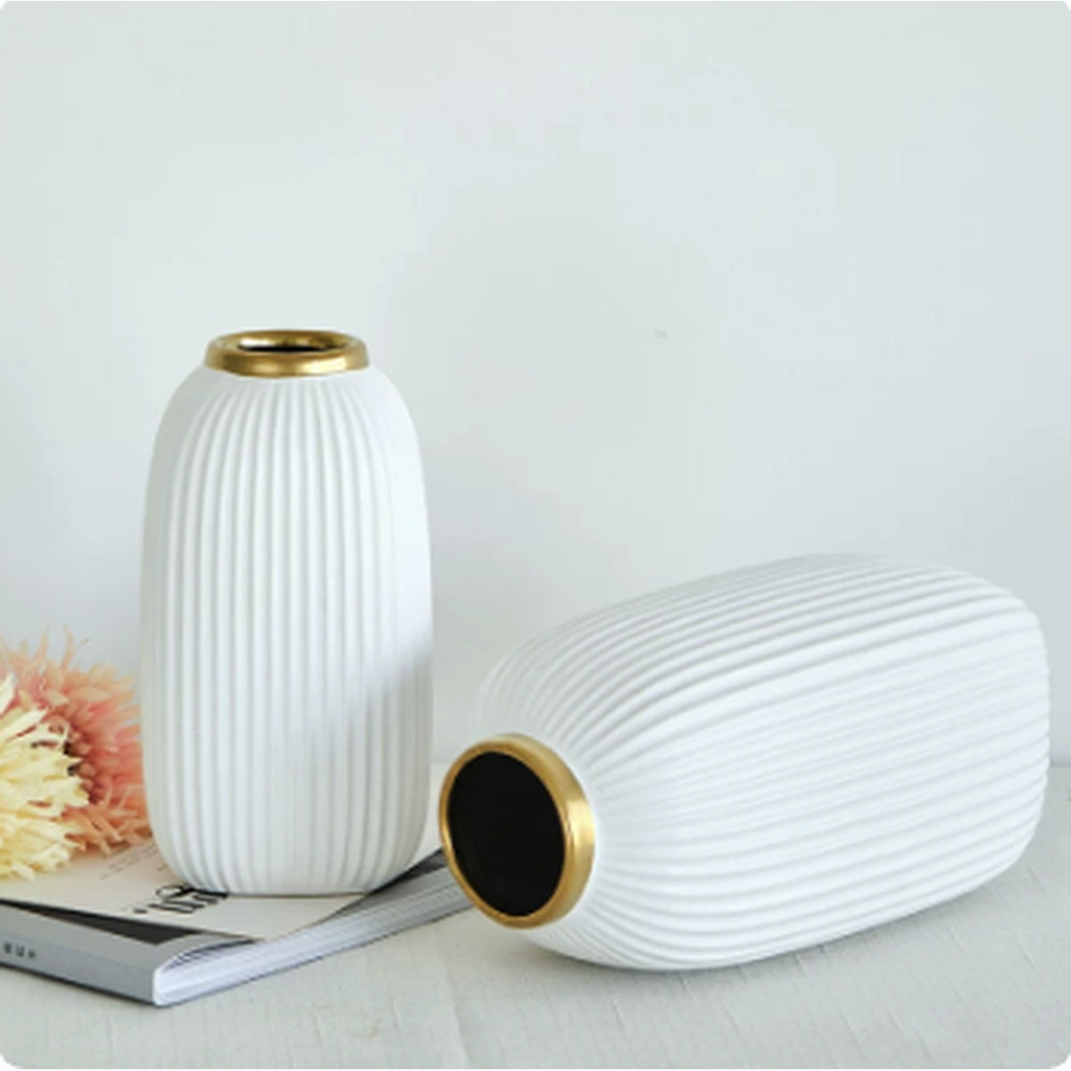 Ribbed white ceramic vase displayed upright and lying down to show gold rim detail