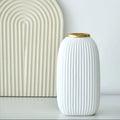 White ribbed ceramic vase with gold rim styled beside minimalist arch decor