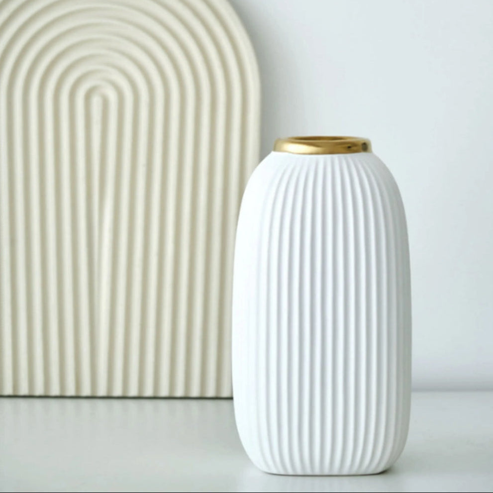White ribbed ceramic vase with gold rim styled beside minimalist arch decor