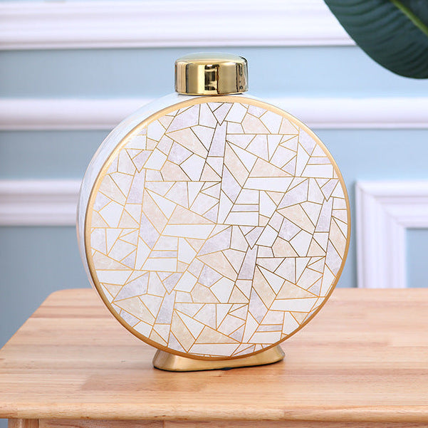 Large round ceramic decorative vase with gold crackle design on a wooden table
