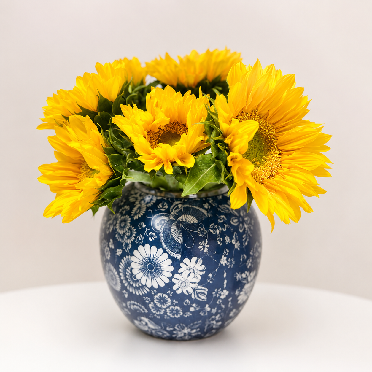Navy floral round ceramic vase with sunflowers on clean neutral background