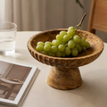 Carved wood centerpiece bowl with green grapes on a table with soft neutral styling
