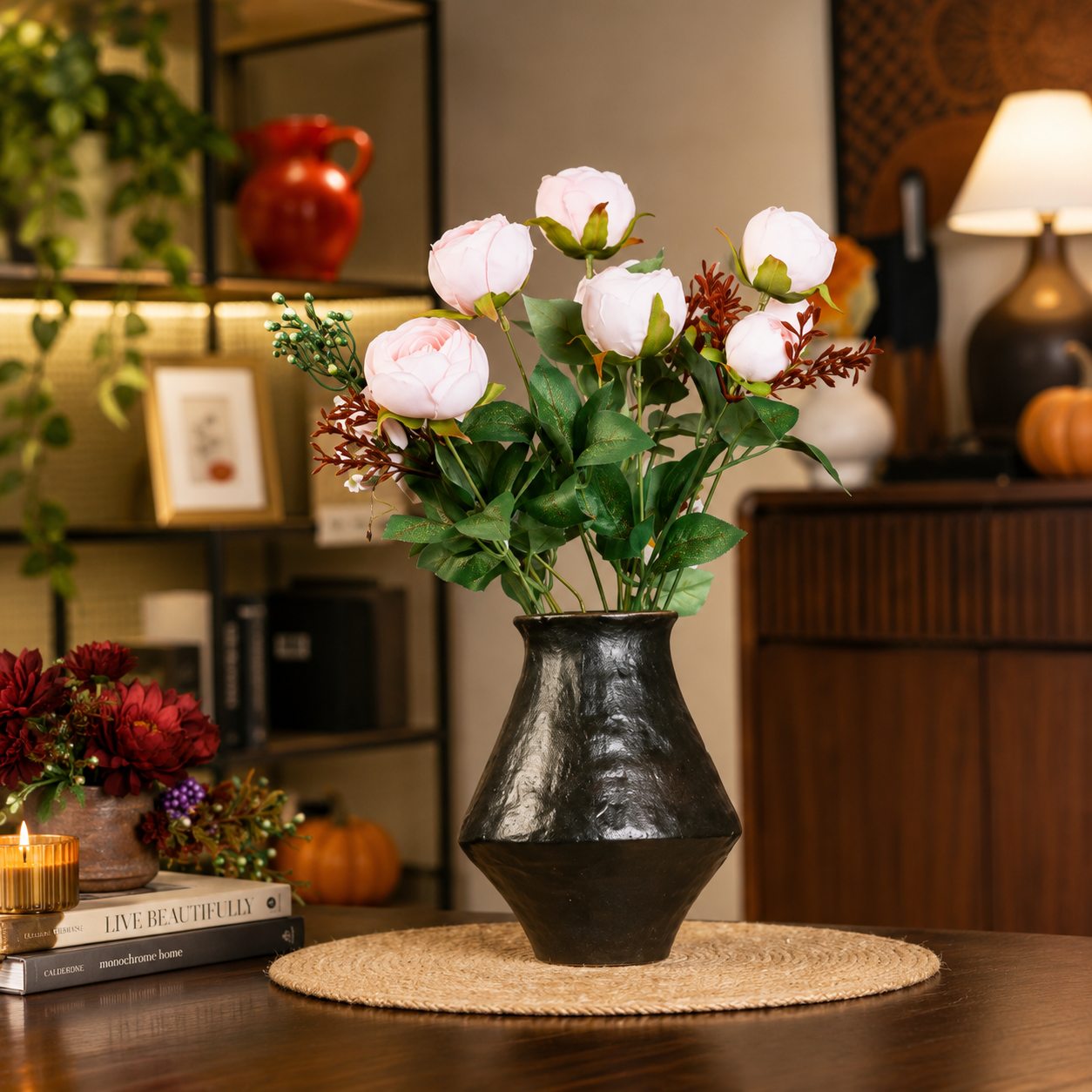 Black rustic ceramic flower vase with pink faux flowers in a warm cozy interior