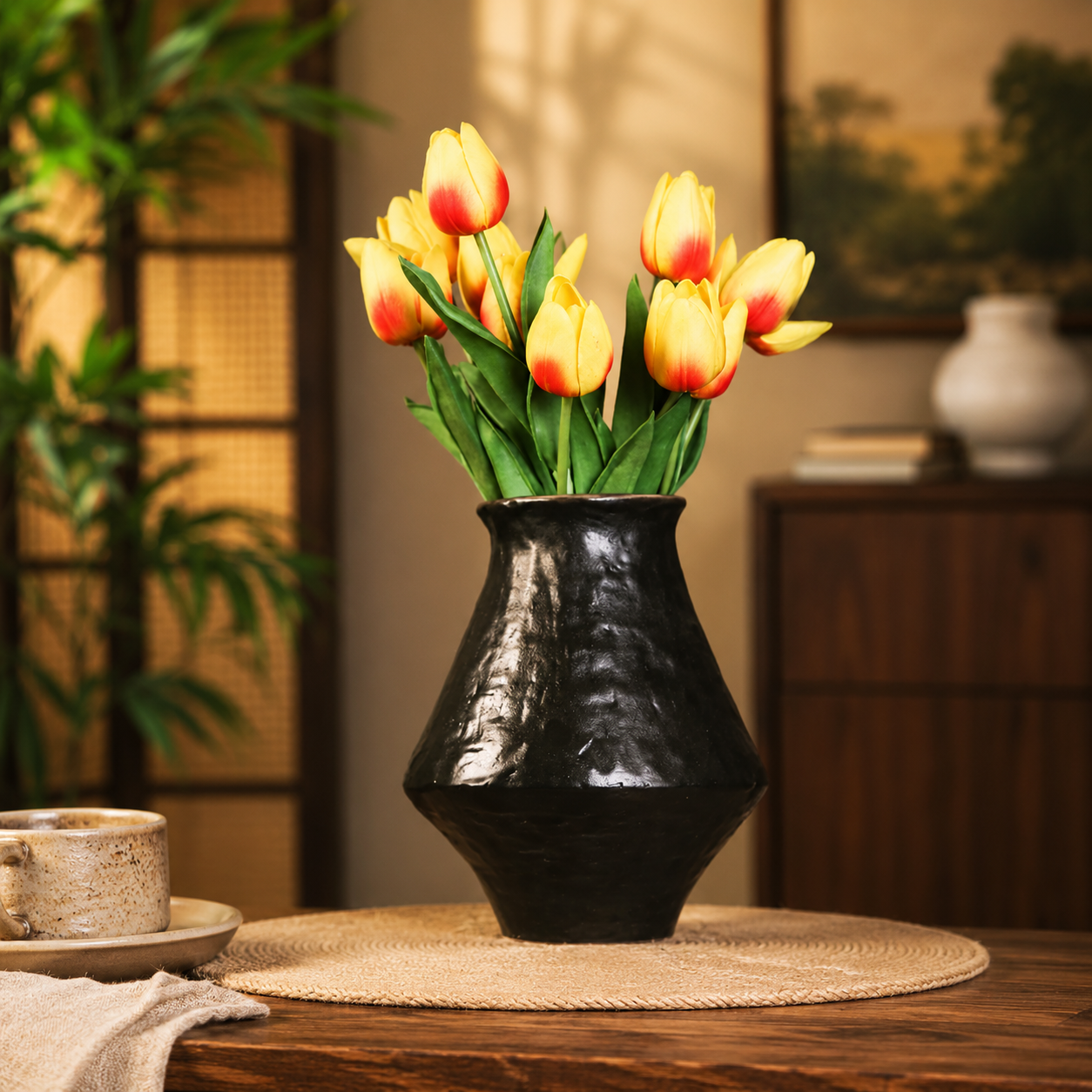 Black rustic ceramic flower vase styled with yellow tulips in a warm home interior