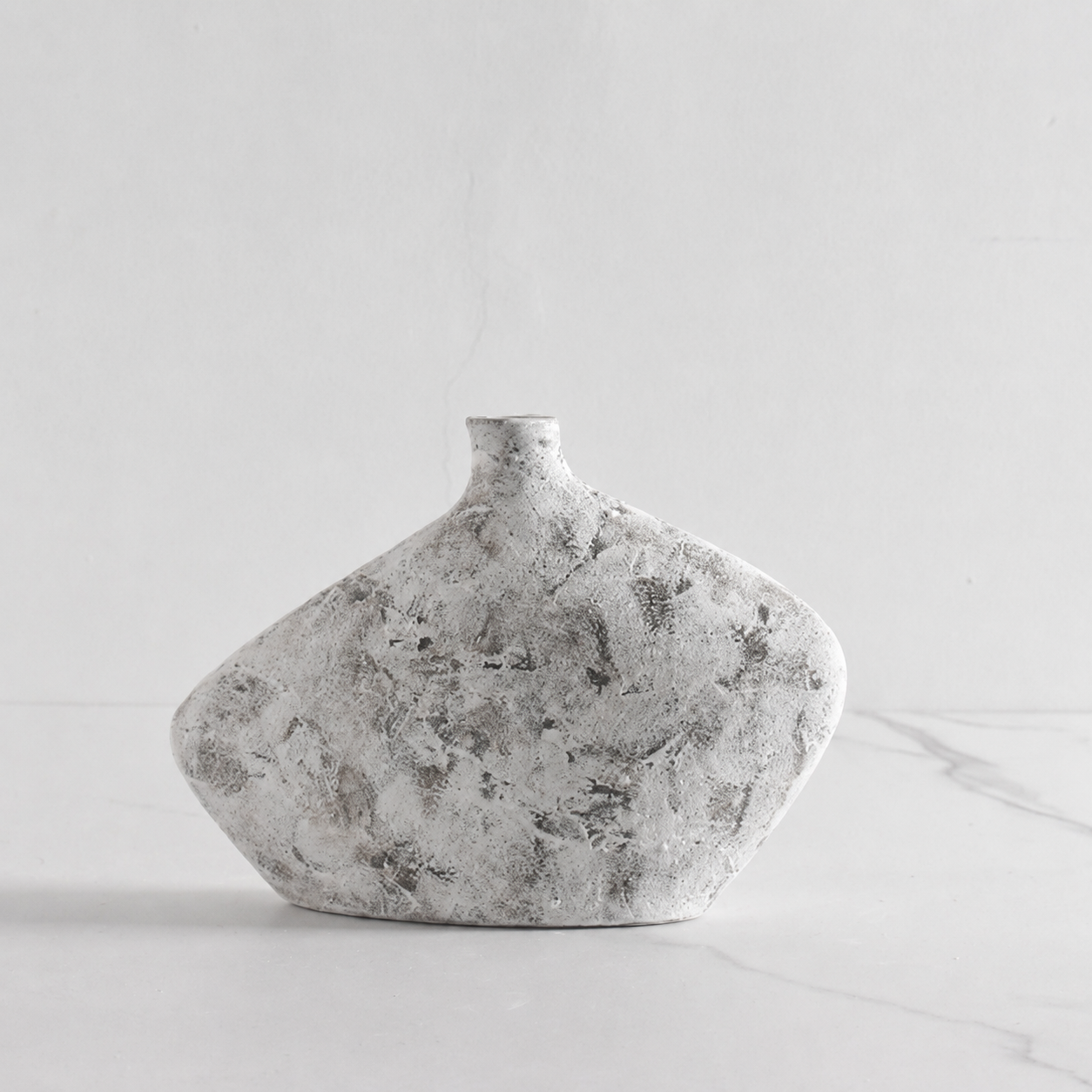 Short rustic gray textured ceramic vase on a marble surface