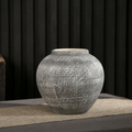 Small round textured gray ceramic decorative vase on a neutral table runner