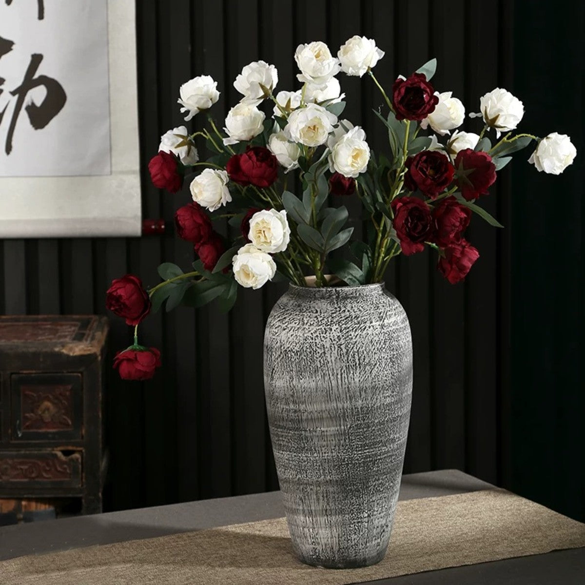 Tall rustic gray ceramic flower vase styled with burgundy and white blooms