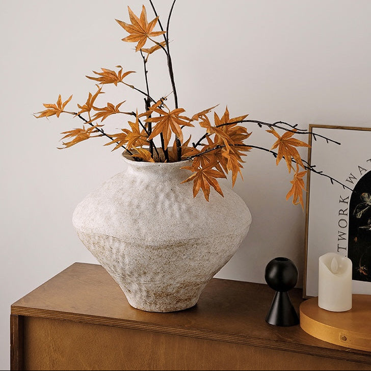 Small wide textured ceramic Wabi Sabi vase with orange maple branches on a wooden console