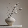 Small rustic ceramic Wabi Sabi vase styled with bare branches on a neutral shelf