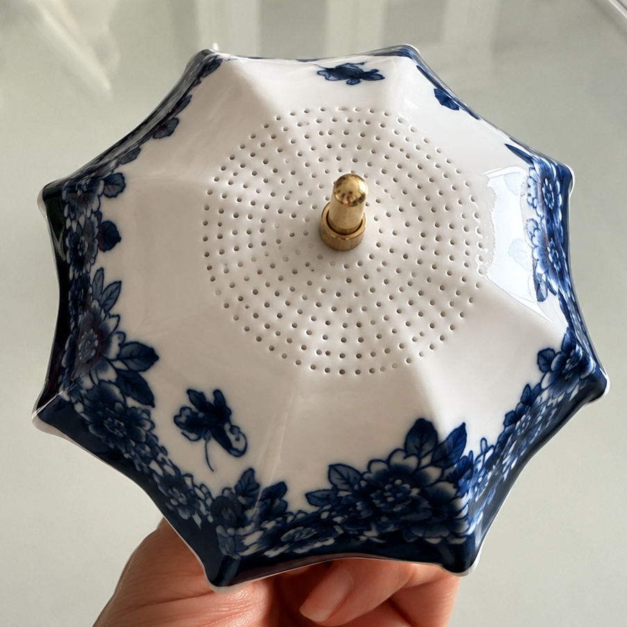 Close-up top view of blue floral ceramic tea strainer showing fine filter holes