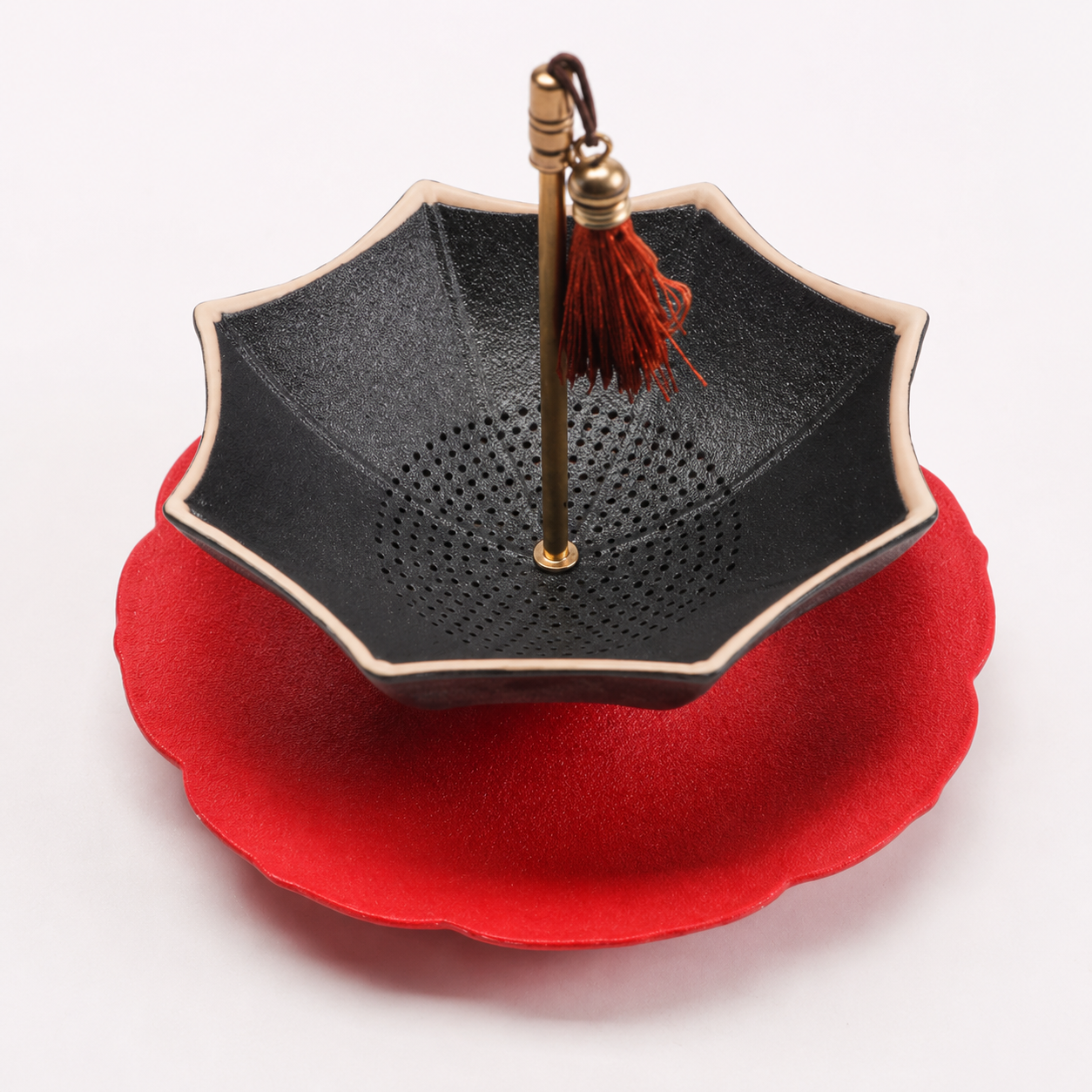 Black and red scalloped ceramic tea strainer with matching drip tray