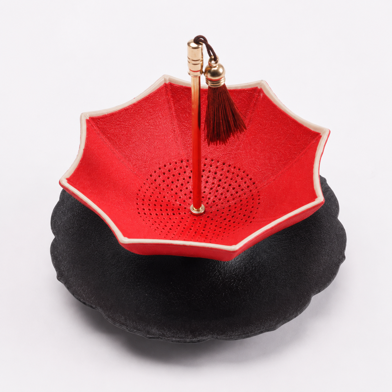 Red and black scalloped ceramic tea strainer with matching drip tray