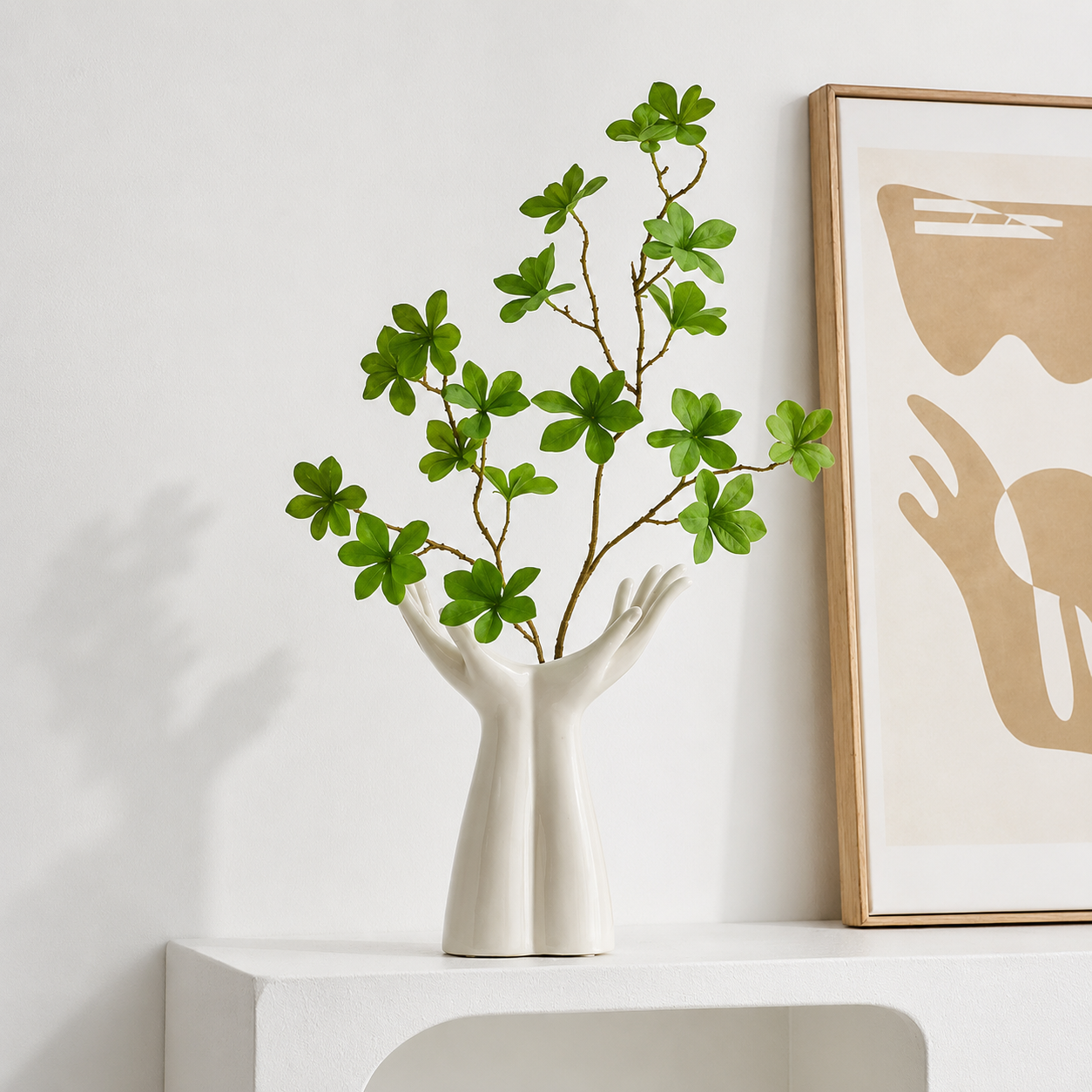 Sculptural ceramic hand vase with green leafy stems for modern tabletop decor