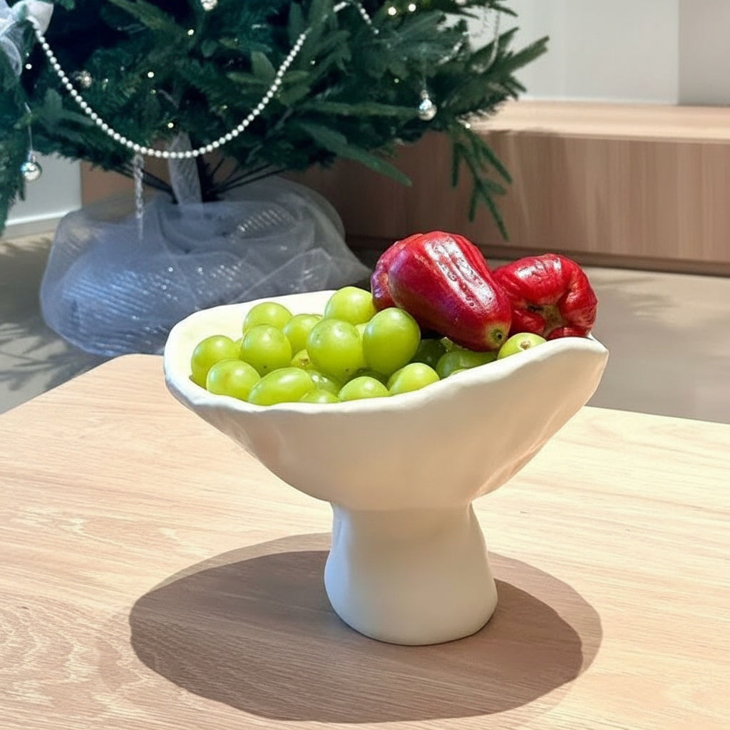 White sculptural ceramic pedestal centerpiece bowl styled with green grapes and fruit
