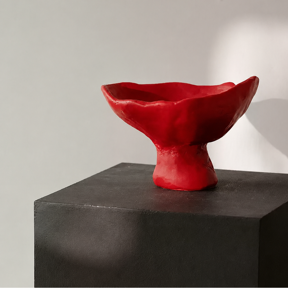 Red sculptural ceramic pedestal centerpiece bowl displayed on black plinth