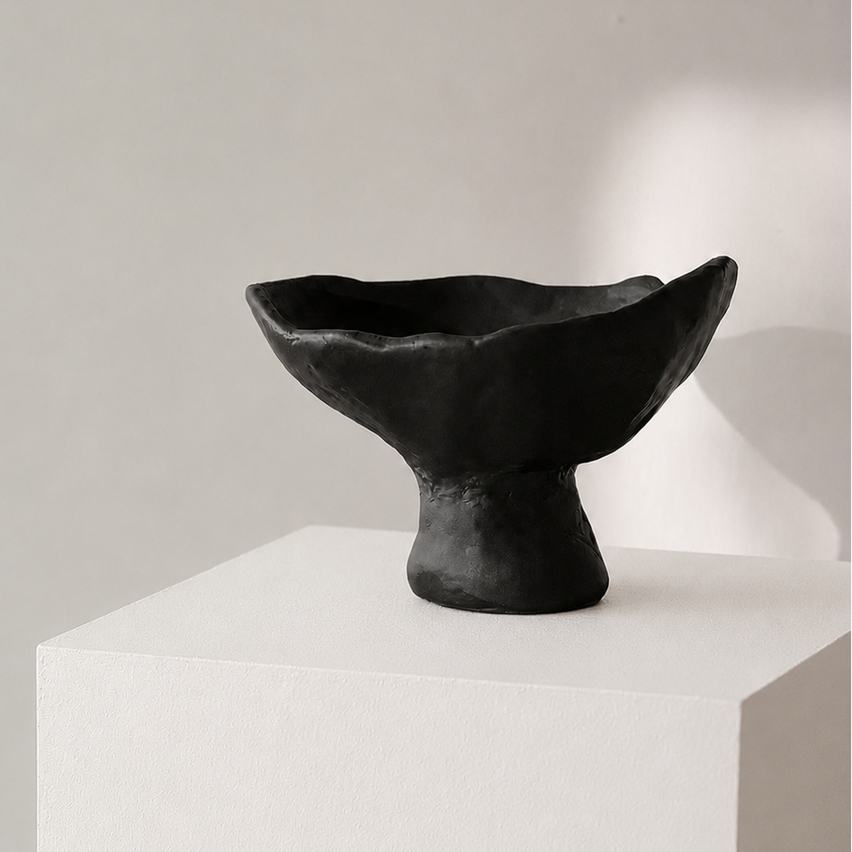 Black ceramic pedestal centerpiece bowl displayed on white plinth
