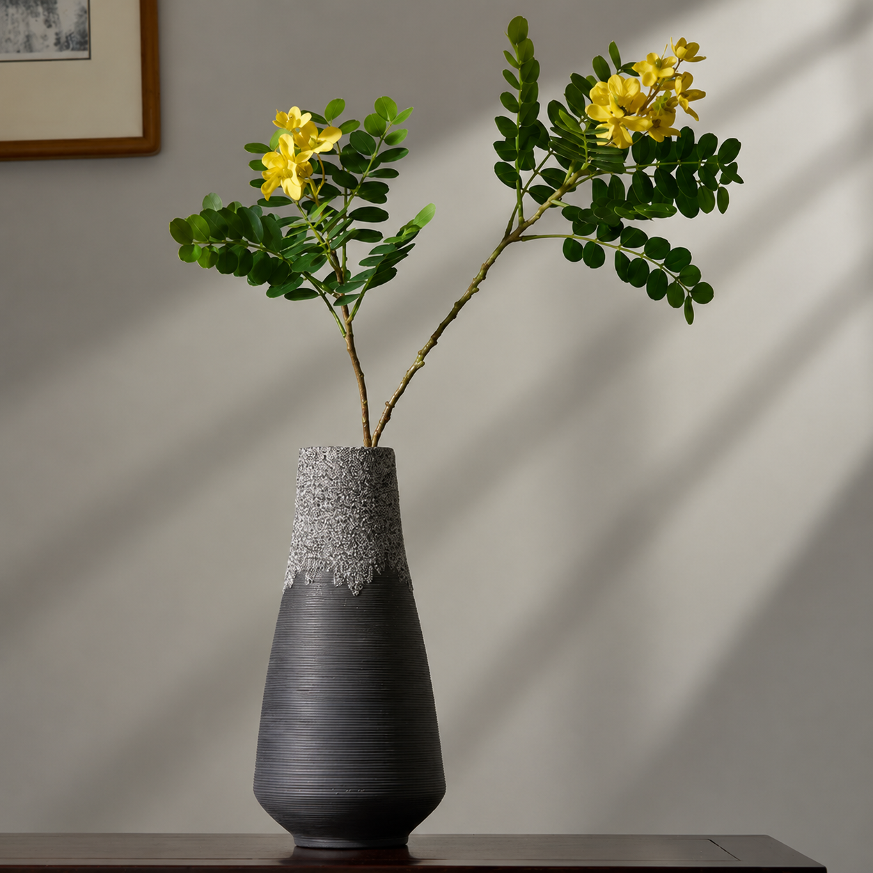 Black sculptural ceramic vase with yellow flowering branches on console table