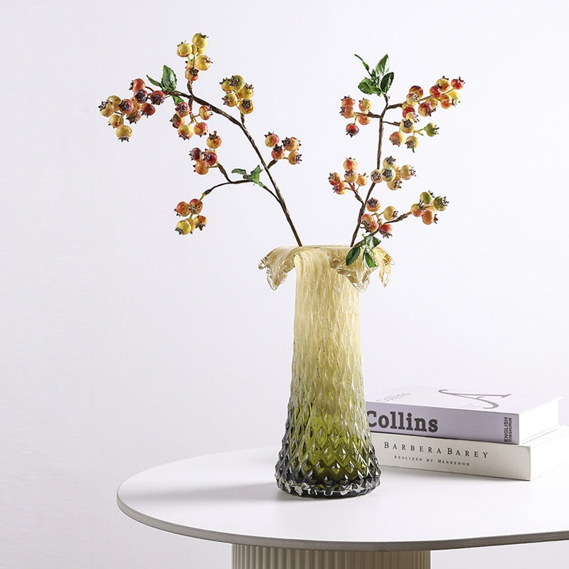Amber green faceted glass vase styled with flowering branches on a modern side table