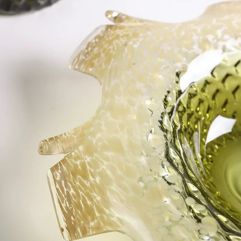 Close up of faceted glass centerpiece bowl showing textured green interior and flowing amber rim