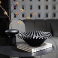 Black ruffled resin centerpiece bowl displayed in dark modern interior