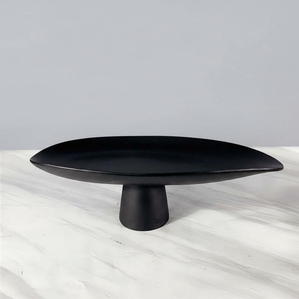 Black resin pedestal centerpiece bowl displayed alone on marble tabletop
