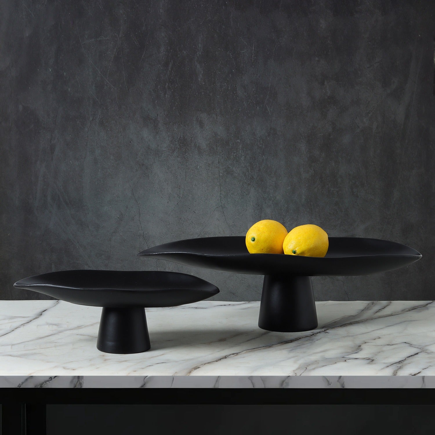 Black resin pedestal centerpiece bowls styled with yellow lemons on marble surface
