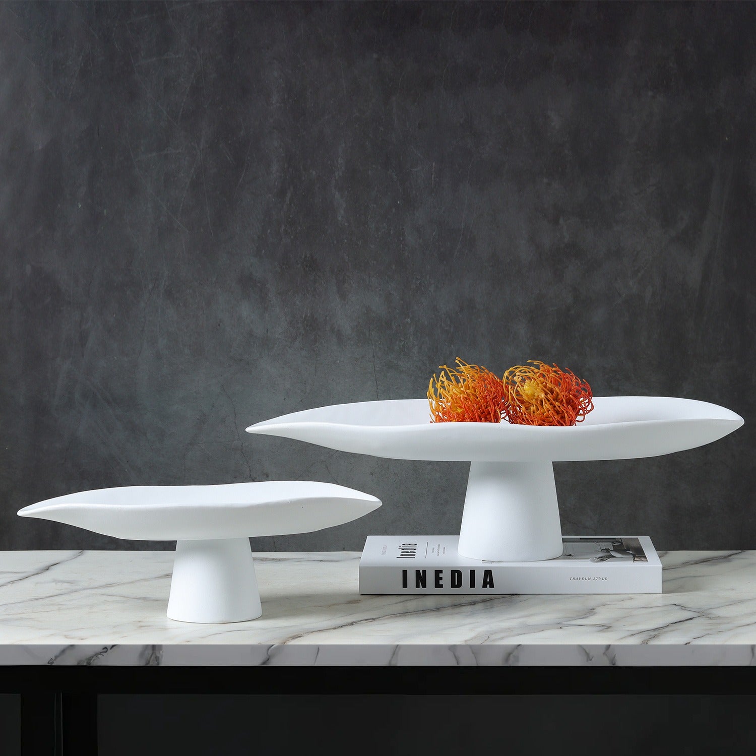 White and black sculptural resin pedestal bowls displayed together with decorative accents