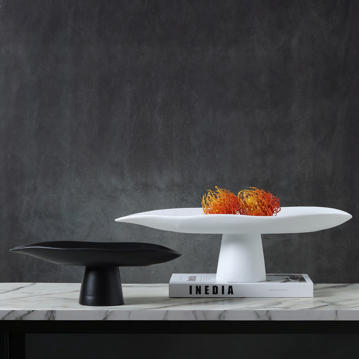 Black and white sculptural resin pedestal centerpiece bowls displayed on modern marble console