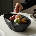 Black sculptural ceramic centerpiece bowl filled with fruit and styled by hand