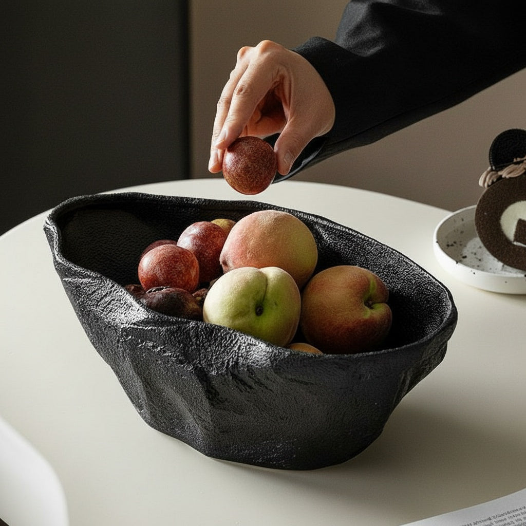 Black sculptural ceramic centerpiece bowl filled with fruit and styled by hand