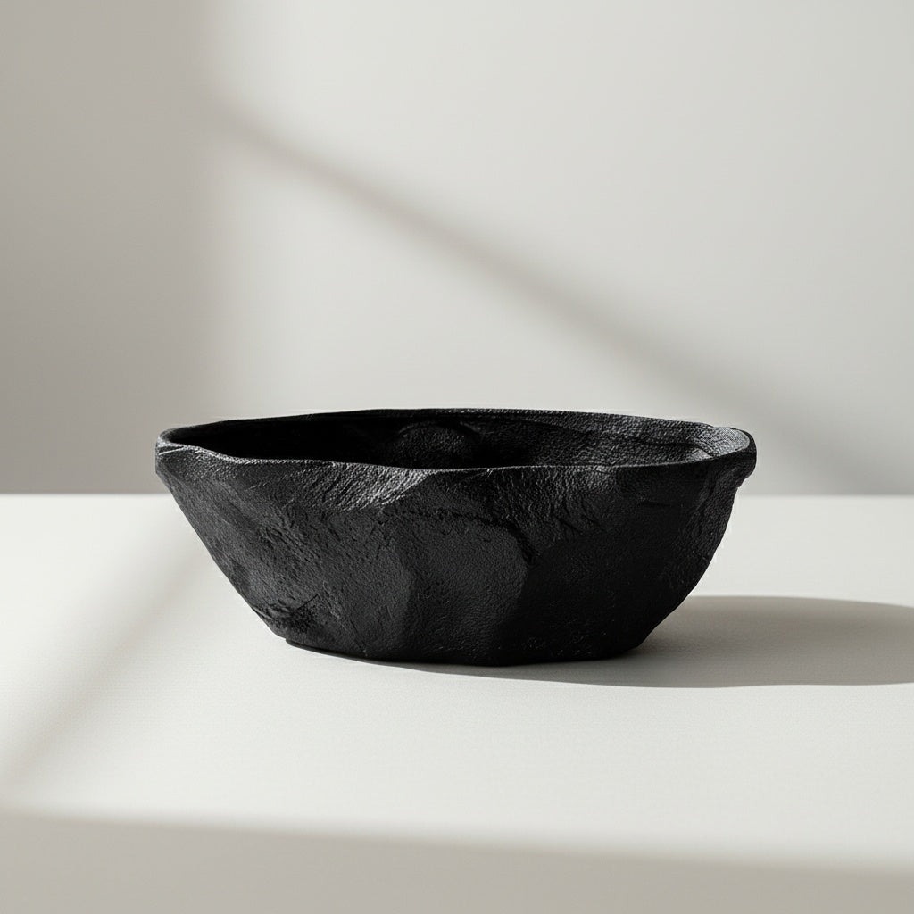 Black textured ceramic centerpiece bowl displayed alone on minimalist pedestal