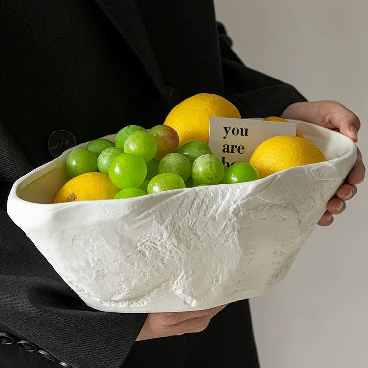 White sculptural ceramic centerpiece bowl held in hand with fruit inside