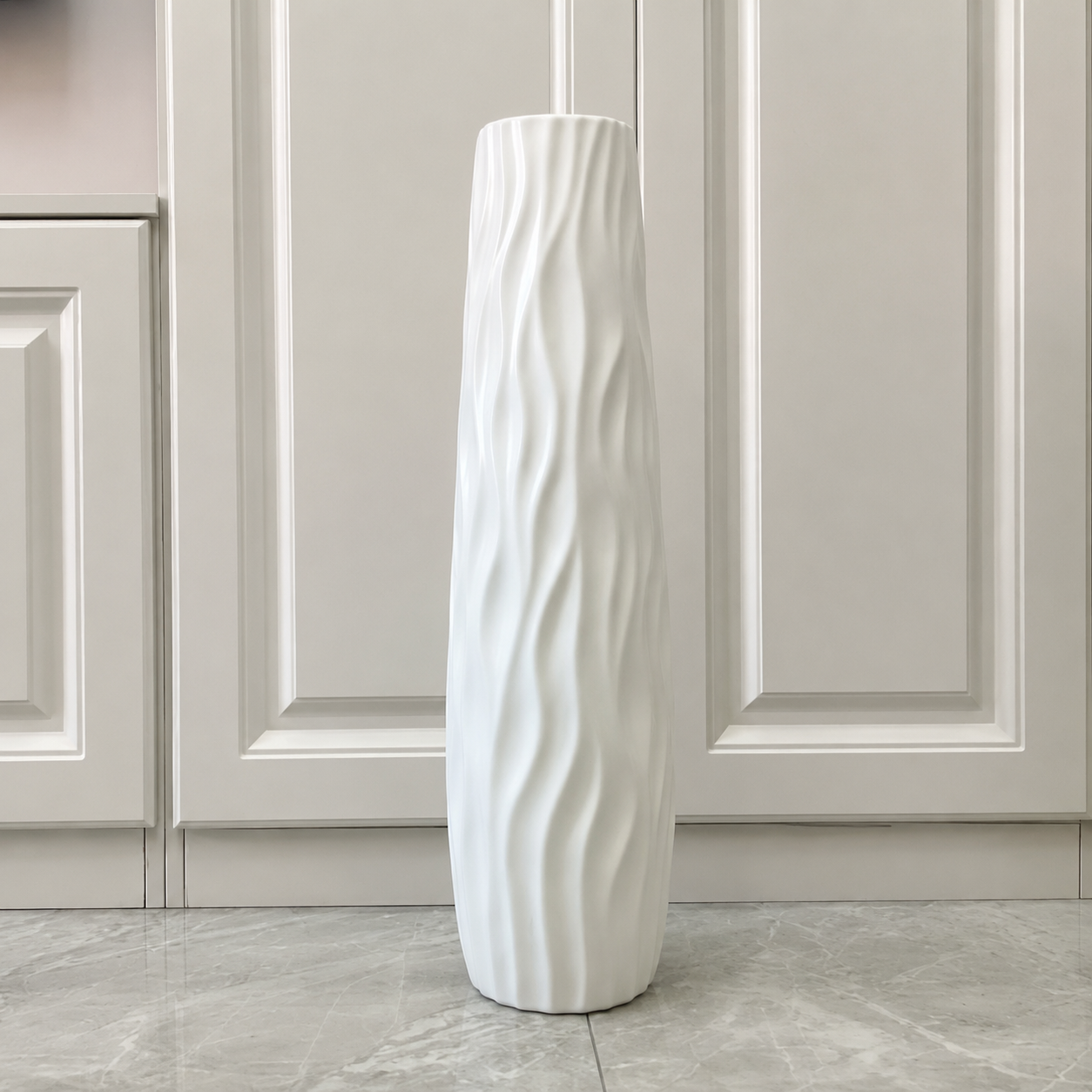 White wavy textured floor vase displayed alone in a bright modern interior